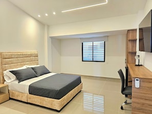 Un dormitorio moderno con cama, mesita de noche y escritorio con silla.