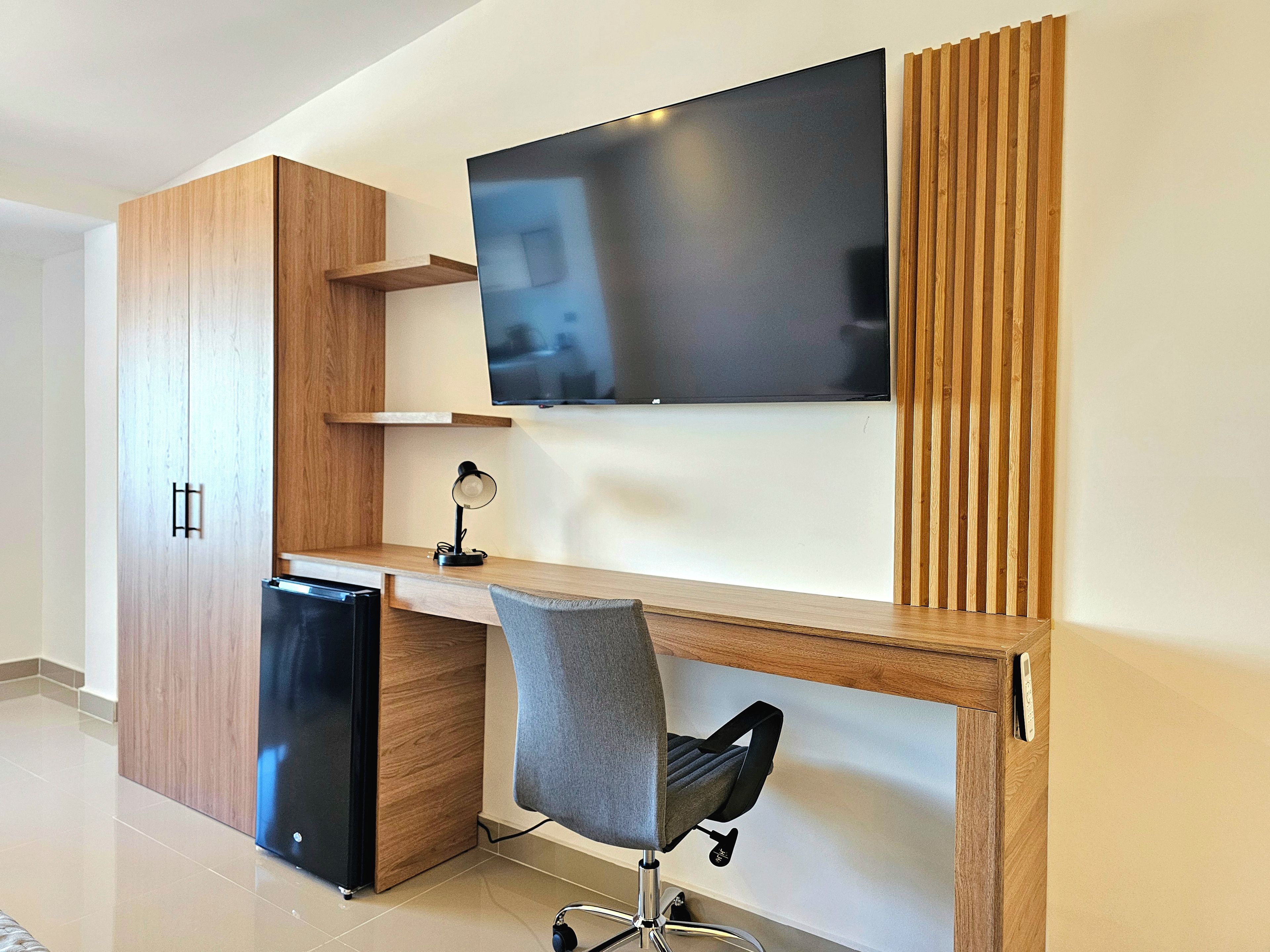 Un espace de bureau moderne comprenant un bureau, une chaise et un téléviseur à écran plat fixé au mur.
