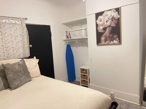 A bedroom with a bed, a door, a shelf with items, and a framed picture on the wall. - Charming Cozy Midtown Cottage near Lake Ella/FSU/FAMU/CIVIC CENTER/TMH (Tallahassee)