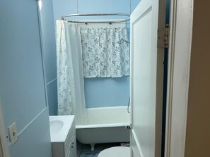 A bathroom with a bathtub, a toilet, and a shower curtain. - Charming Cozy Midtown Cottage near Lake Ella/FSU/FAMU/CIVIC CENTER/TMH (Tallahassee)