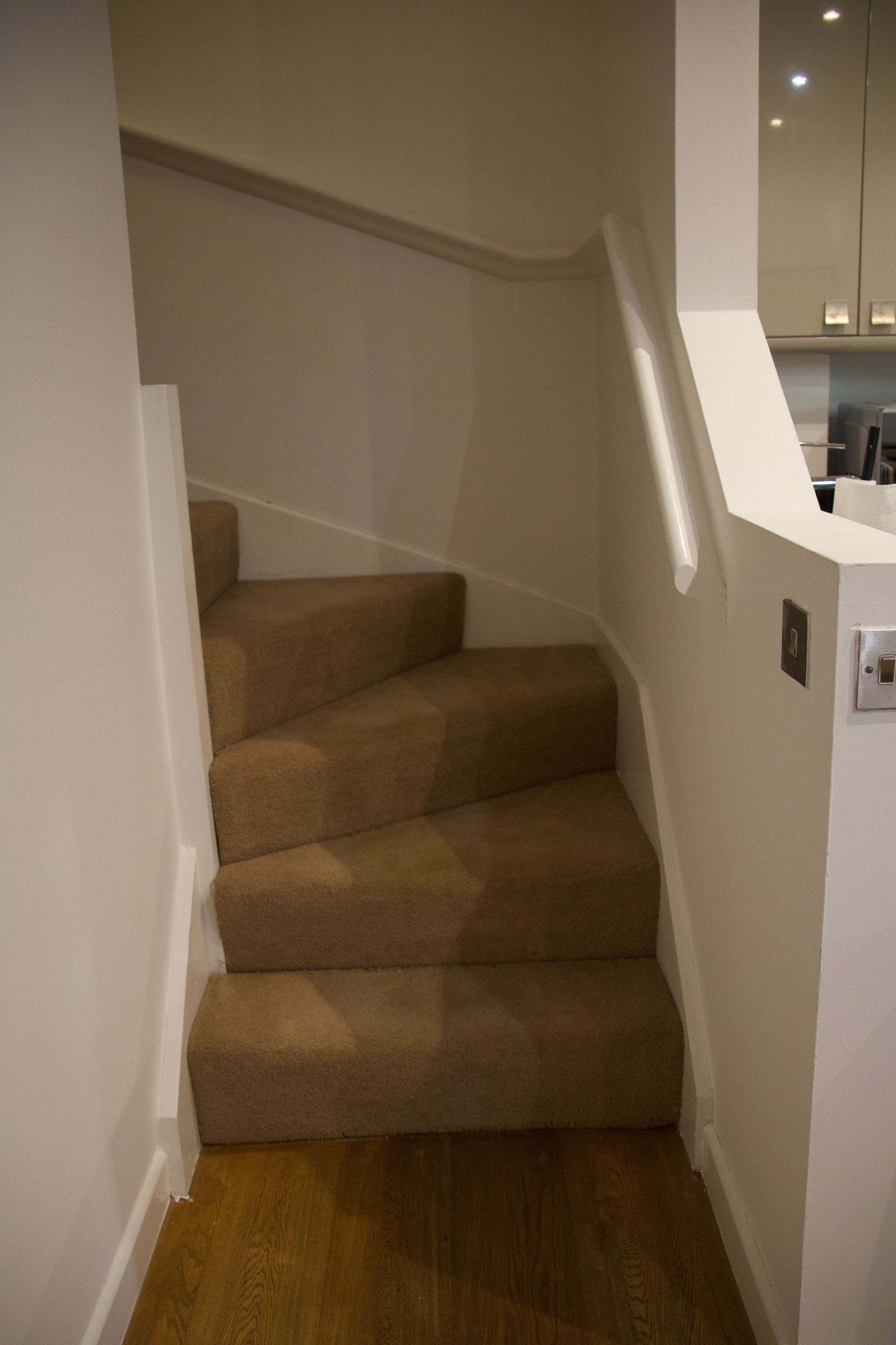 A staircase with carpeted steps leading to a landing.