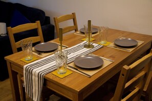 A wooden dining table set with plates, glasses, cutlery, and a striped table runner. - Stylish and modern Oxford City Centre apartment. (Oxford)