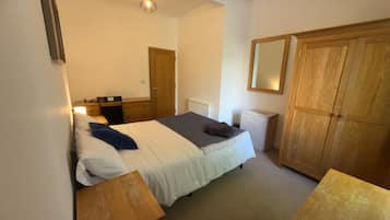 A bedroom with a bed, bedside tables, a wardrobe, a mirror, and a radiator.
