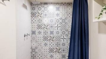 Un baño pequeño con ducha, inodoro y pared con diseño.