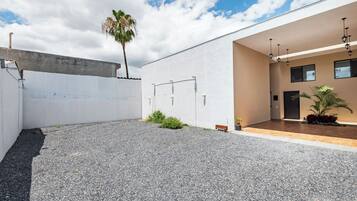 A modern building with a gravel courtyard, a palm tree, and a wooden bench.