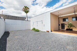 A modern building with a gravel courtyard, a palm tree, and a wooden bench. - Hacienda Tapia (Monterrey)