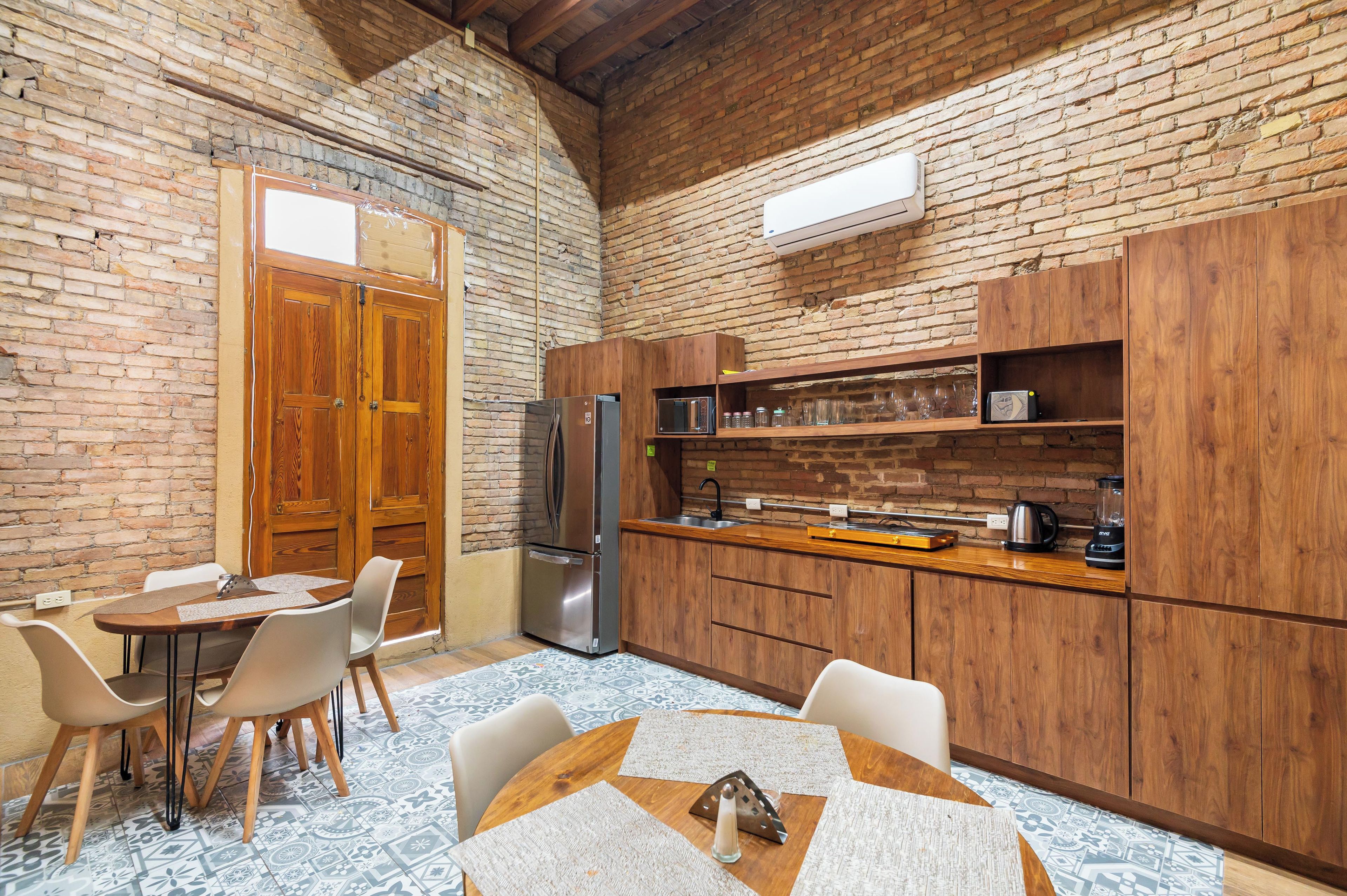 A kitchen with wooden cabinets, a stainless steel refrigerator, and a dining area with a table and chairs.