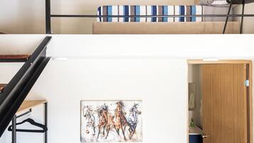 A multi-level interior with a staircase, a ceiling fan, a painting, and a blue sofa.