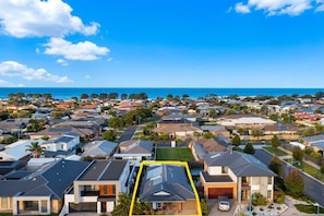 Un quartier résidentiel avec des maisons, dont certaines sont équipées de panneaux solaires, et qui offre une vue sur l’océan.