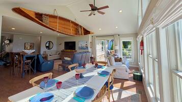 A spacious dining area with a high ceiling, a ceiling fan, and a view of the outdoors.