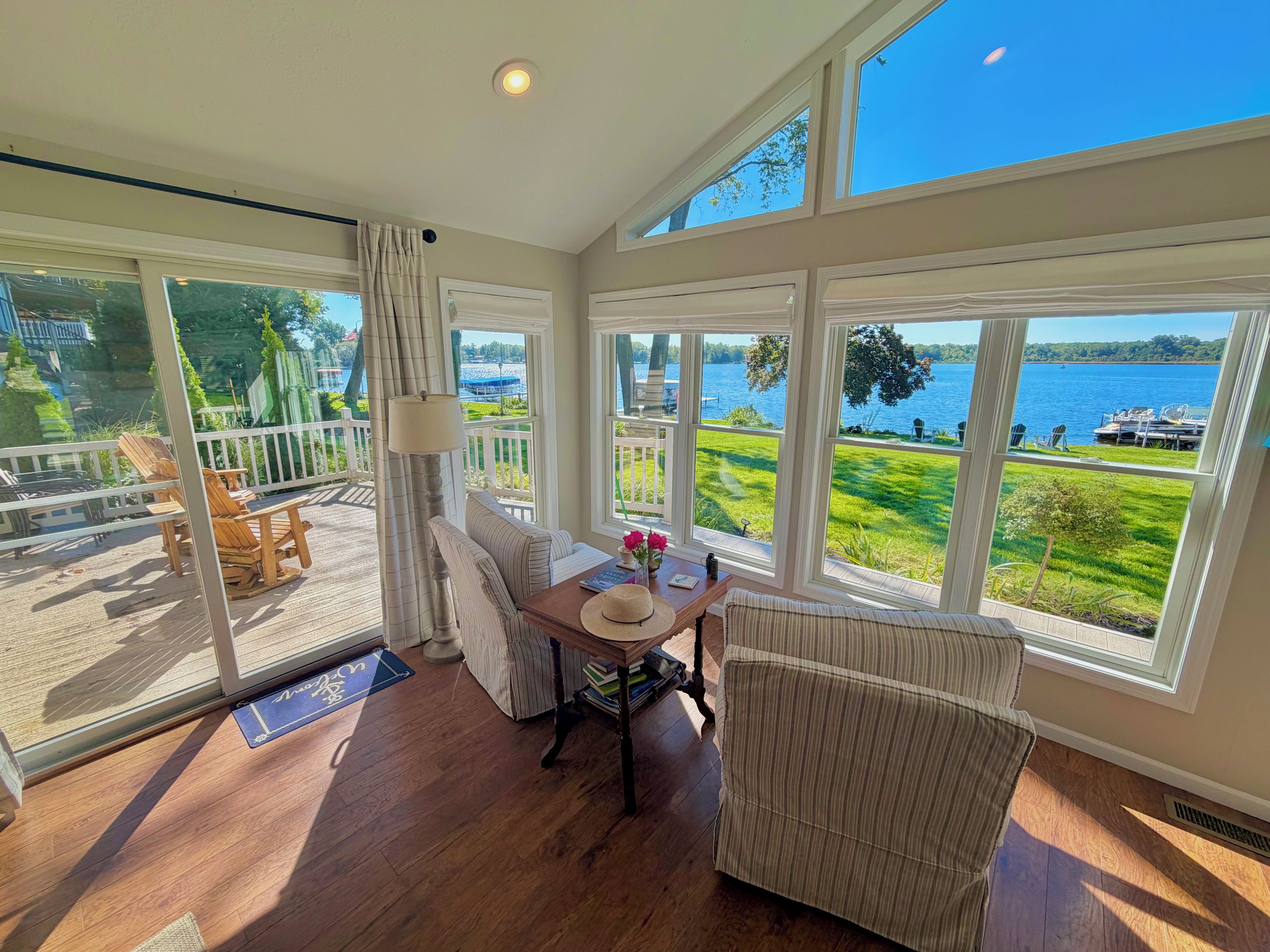 Una habitación con vista a un lago, una mesa de comedor con sillas, una lámpara y una ventana con cortinas.