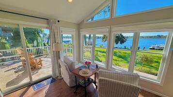 Una habitación con vista a un lago, una mesa de comedor con sillas, una lámpara y una ventana con cortinas.
