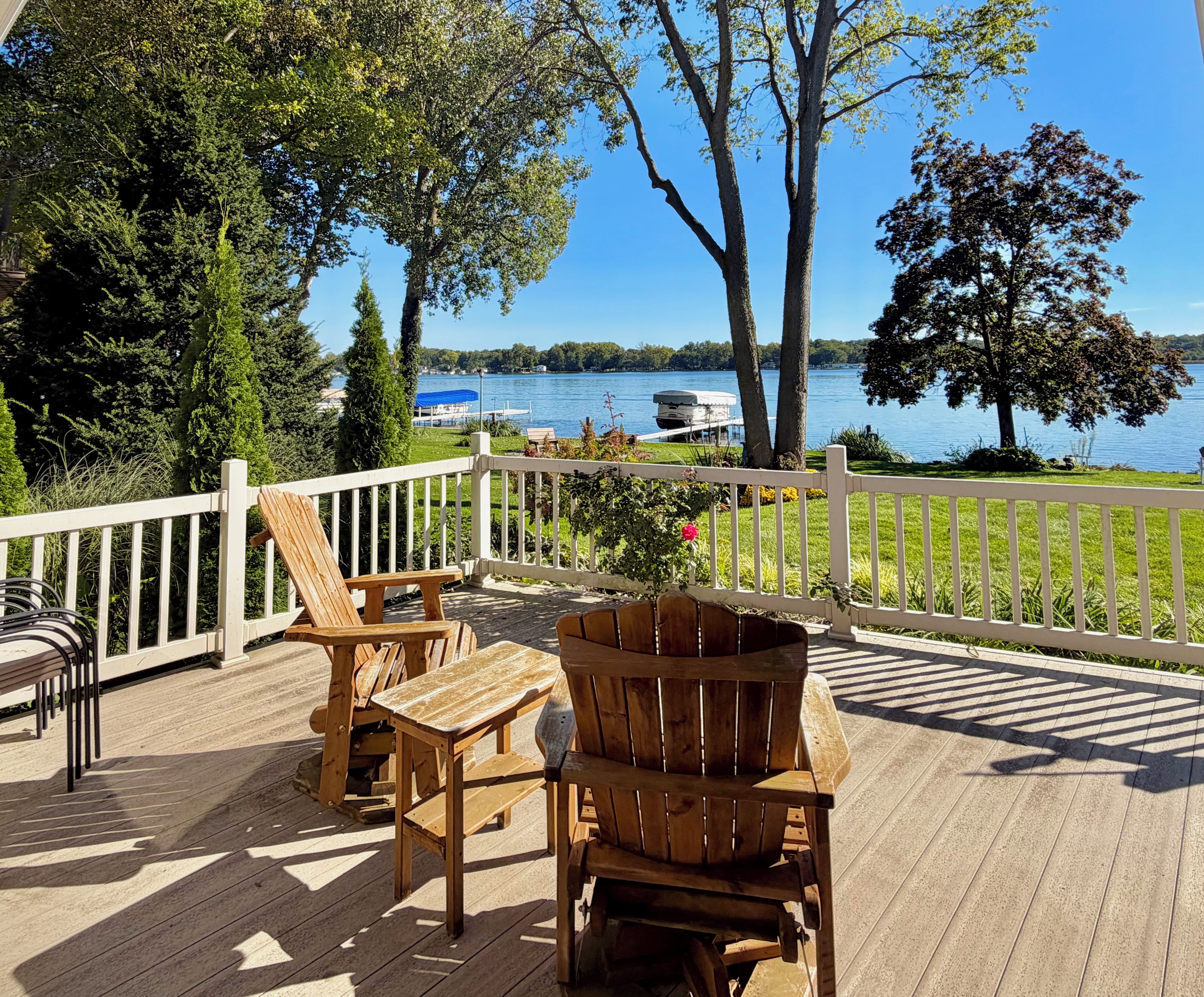 A wooden deck with outdoor furniture overlooking a lake.