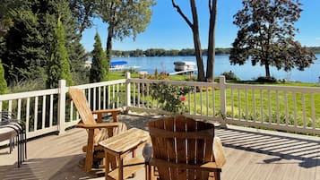 A wooden deck with outdoor furniture overlooking a lake.