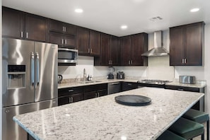 A modern kitchen with stainless steel appliances, dark wood cabinets, and a granite countertop. - NEW| The Tipsy Cactus Old Town Oasis|Pool+Bar+Putt (Scottsdale)