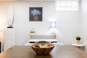 A room with a wooden table, a white cabinet, a framed artwork, a lamp, and a small plant. - Sciota Suite | Private Entrance & Workspace (Peoria Heights)