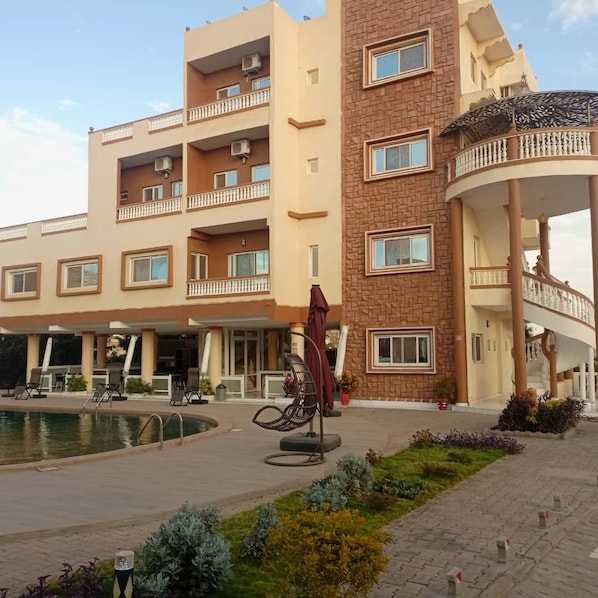 Un hôtel à plusieurs étages doté de balcons, d’une piscine et d’un espace extérieur aménagé pour s’asseoir.