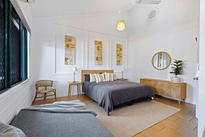 A bedroom with a bed, bedside tables, a chair, artwork on the walls, and a window.
