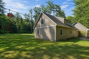 A two-story house with a sloped roof, a front porch, and a swing set in the yard. - Cranmore & Story Land Hot Tub + Sauna Sleeps 10 (Conway)