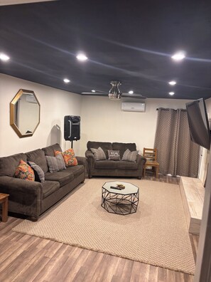 A living room with two sofas, a coffee table, a ceiling fan, and a mounted TV. - Come relax, recharge at Desert Oasis. (Rio Rancho)
