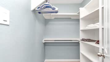 A compact storage area with white shelving, a hanging rack, and a wooden floor.