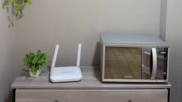 Un microondas y un router blanco sobre un cajón de madera.