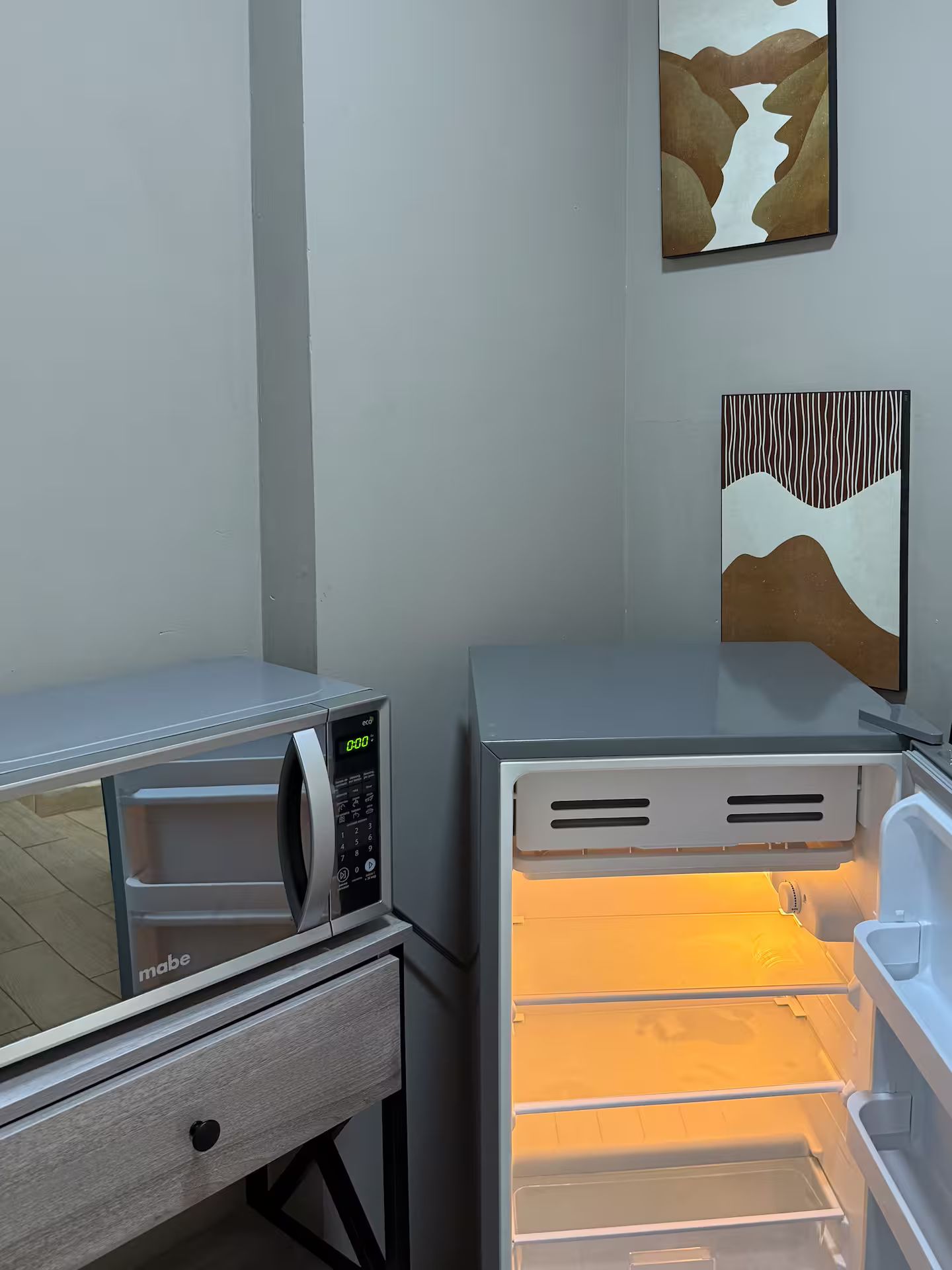 A kitchenette with a microwave, a refrigerator, and a drawer unit.