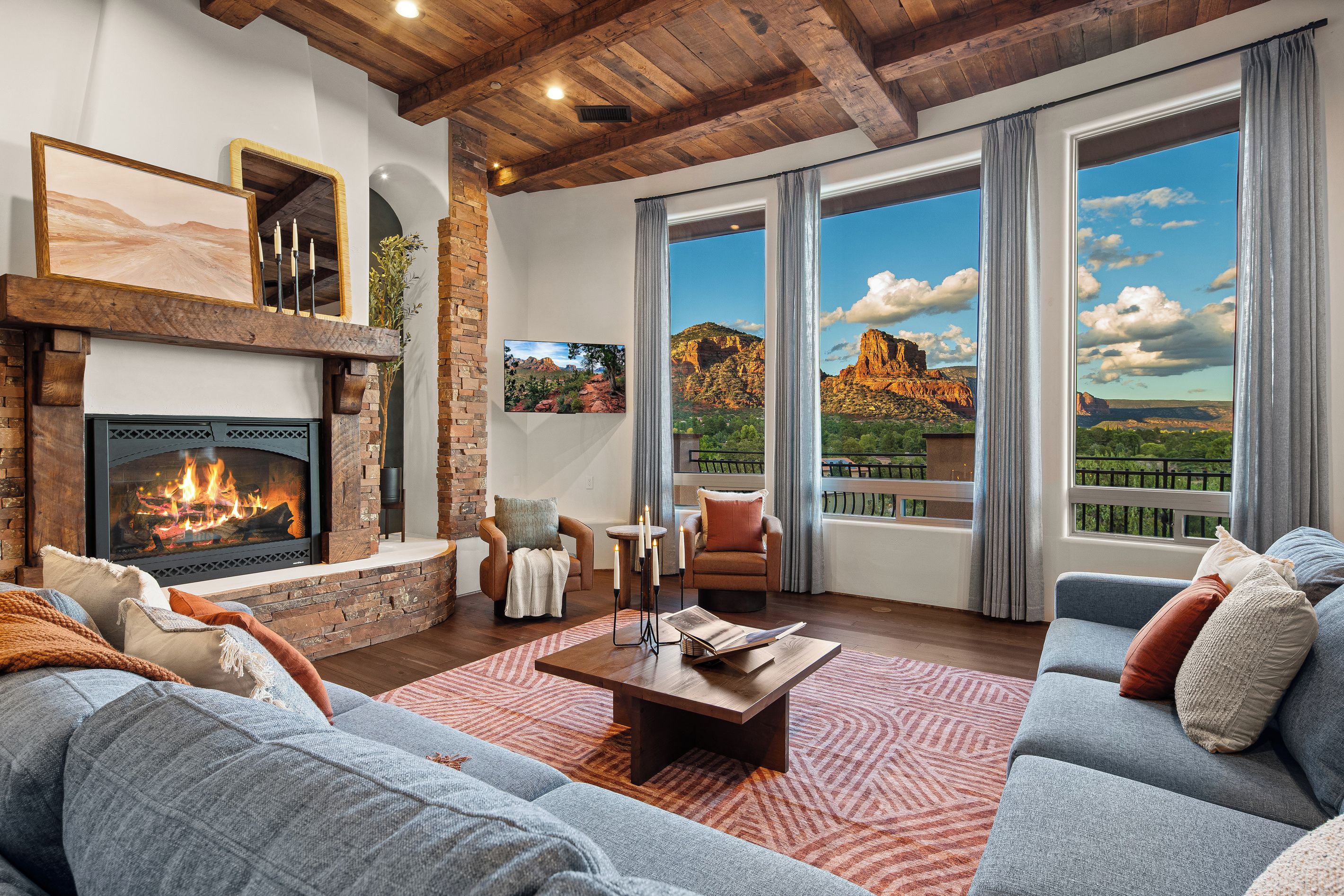 Amplia sala de estar con chimenea, asientos cómodos y ventanas grandes con vistas a un paisaje montañoso.