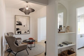 A modern living room with a large abstract painting, a round coffee table, and a unique hanging light fixture. - Stylish Central Aveiro Stay | 3BR + Office (Aveiro)