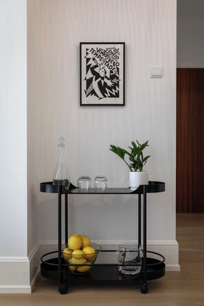 A black metal console table with a bowl of lemons, a potted plant, and a glass bottle. - Stylish Central Aveiro Stay | 3BR + Office (Aveiro)