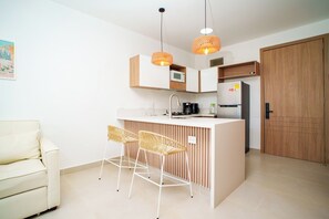 Eine moderne Küche mit einer zentralen Kochinsel, Barhocker, einem weißen Sofa und einer Holztür.