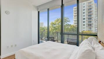 A bedroom with a large bed, a window, and a view of a building.
