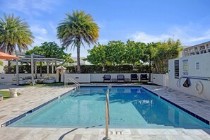 Ein rechteckiger Pool mit Metallgeländer, umgeben von einer gefliesten Liegefläche.