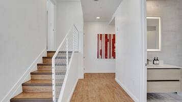 A modern interior with a wooden staircase, a minimalist bathroom, and a red abstract artwork on the wall.