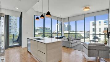 A modern kitchen with a central island, large windows, and a view of the cityscape.