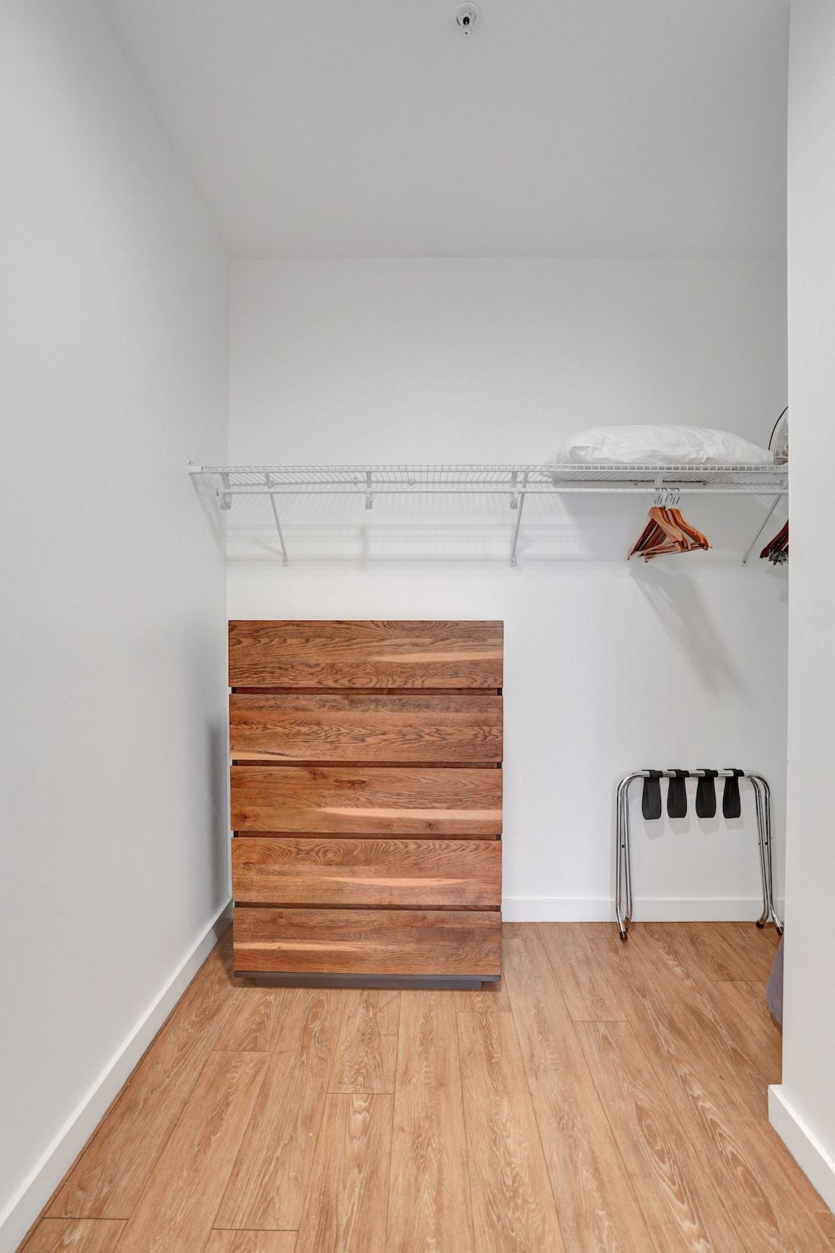 A room with a wooden bench, a metal rack, and a white wall.