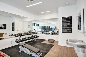Un gimnàs modern amb equipament d'exercici, una banca i una paret amb miralls.