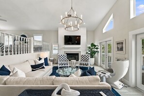 A modern living room with a sofa, armchairs, a glass coffee table, a fireplace, and a TV mounted on the wall. - Coastal Paradise | Waterfront, Heated Pool, Hot Tub & Dock Near Bonita Beach (Bonita Springs)