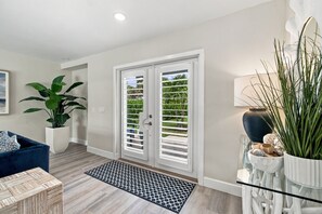 A modern interior with a blue sofa, a potted plant, a patterned rug, and a glass table with decorative items. - Coastal Paradise | Waterfront, Heated Pool, Hot Tub & Dock Near Bonita Beach (Bonita Springs)