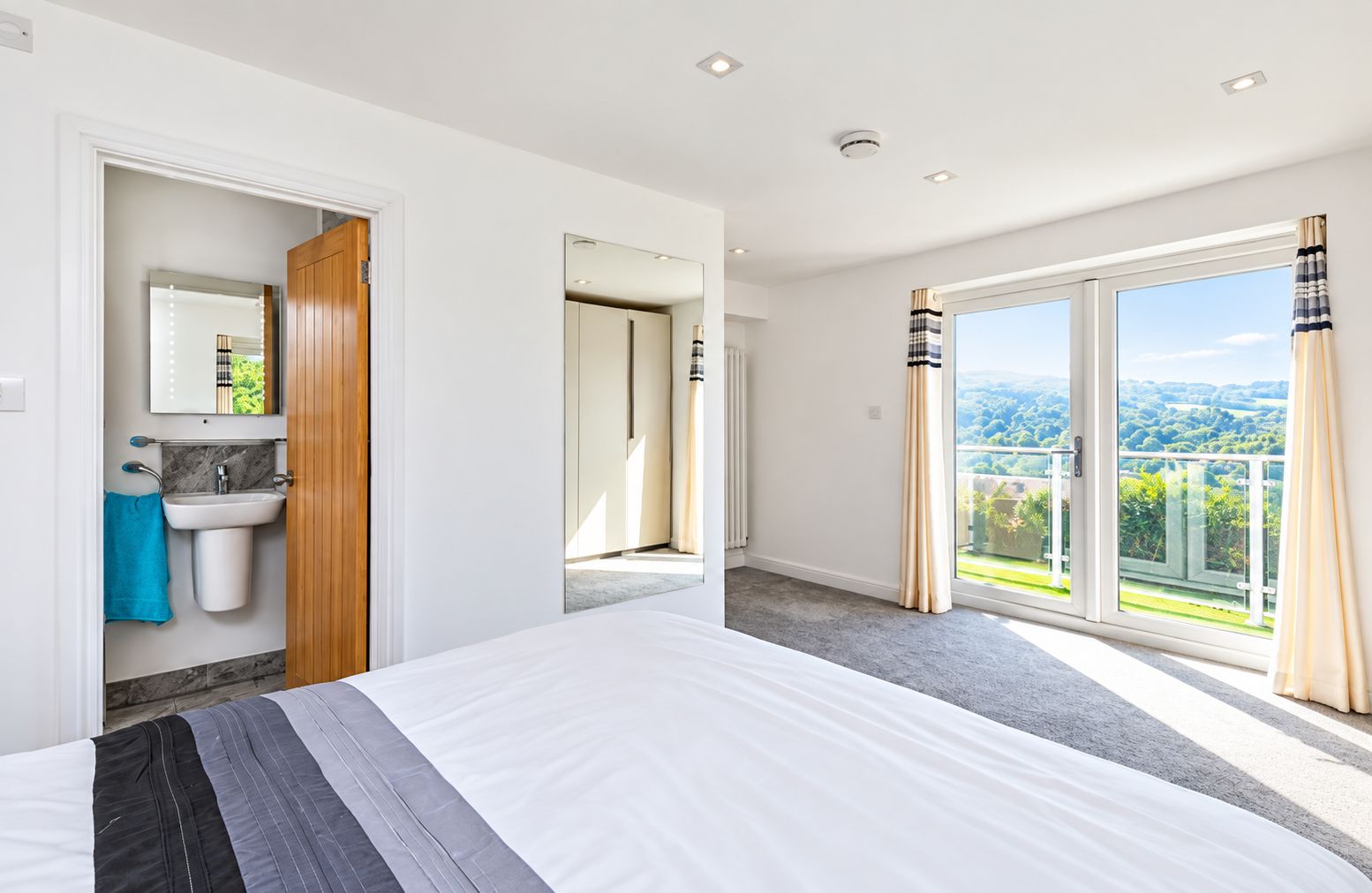 Ein Hotelzimmer mit einem Bett, einem Badezimmer mit Waschbecken, einem Spiegel und Blick ins Freie.
