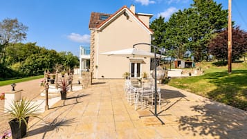 A house with a patio, outdoor furniture, and a garden.
