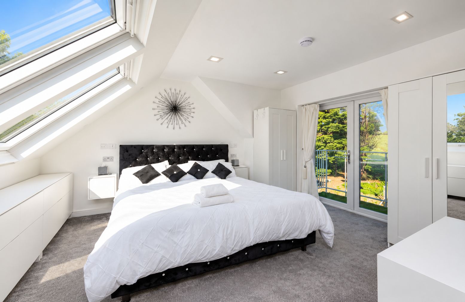 Quarto moderno com cama grande, claraboia, guarda-roupa embutido e vista para o exterior.