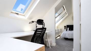 A modern bedroom with a skylight, a desk, and a bed.