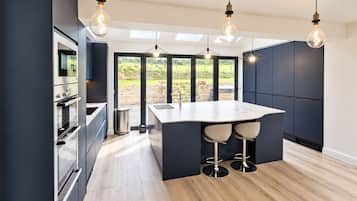 Una cucina moderna con isola centrale, illuminazione a sospensione e vista panoramica attraverso ampie finestre.