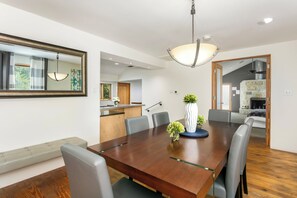 A dining area with a wooden table, grey chairs, and a hanging light fixture. - 406 Lodge A | King Bed, Hot Tub, Walk to Main St. (Fredericksburg)