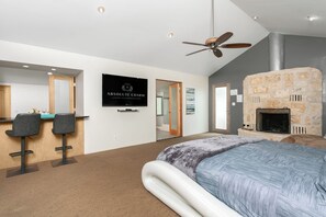 Een moderne slaapkamer met een bed, een stenen openhaard, een plafondventilator en een bordje met 'Absolute Charm Luxury Accommodations'.