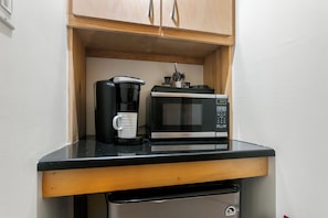 A kitchenette with a coffee maker, microwave, and a small trash bin. - King-bed Fredericksburg hideaway with Wi-Fi, fire pit, and pet-friendly charm. (Fredericksburg)