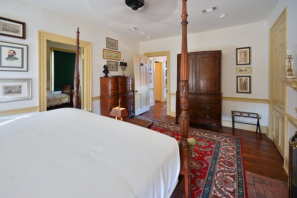 A spacious bedroom with a large bed, a wooden wardrobe, and a red patterned rug.
