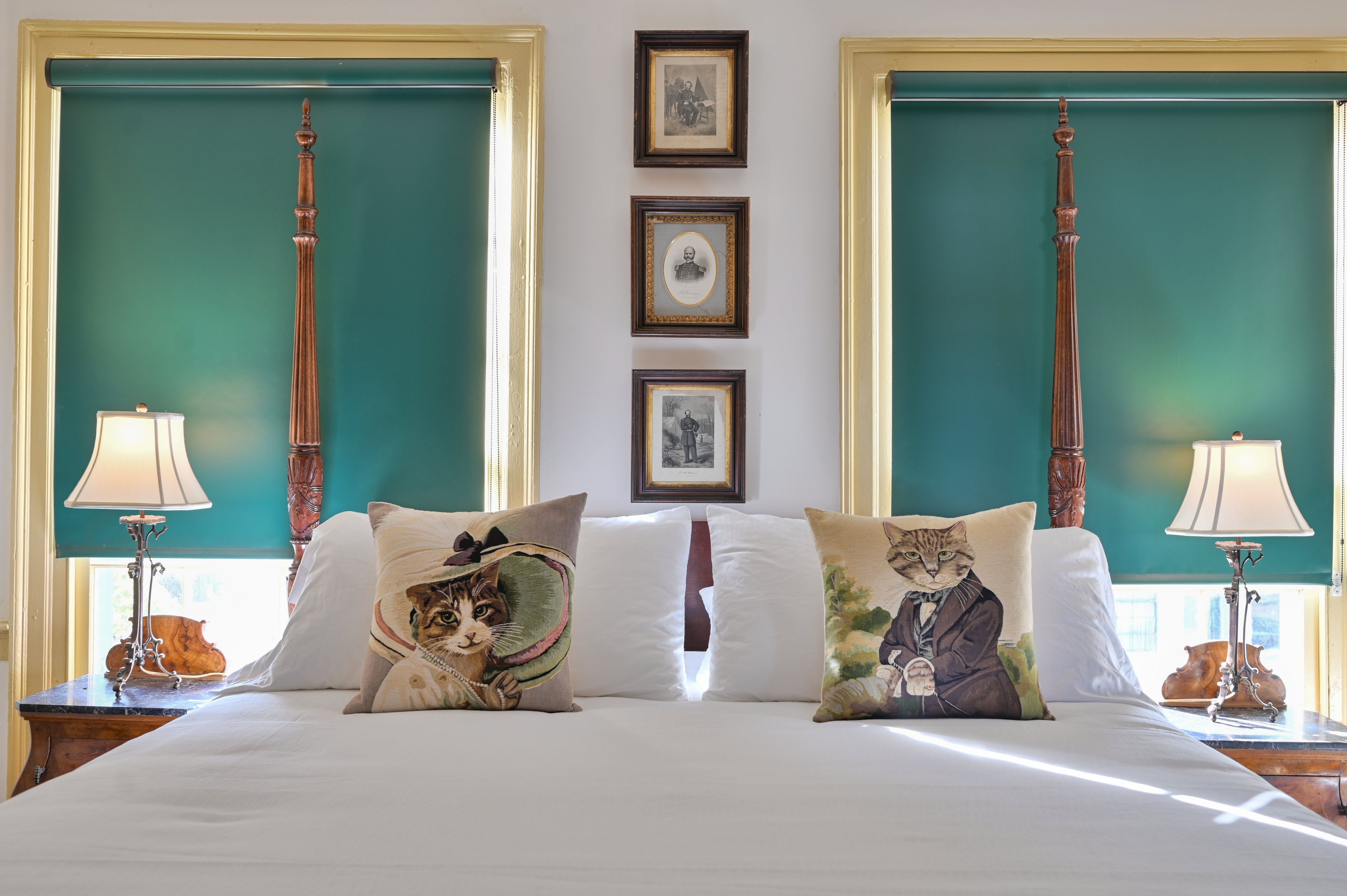 Une chambre d’hôtel avec un grand lit, deux tables de chevet, un mur vert et des tableaux encadrés.
