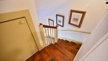 Un escalier en bois, avec une porte blanche en haut et un palier recouvert de moquette.